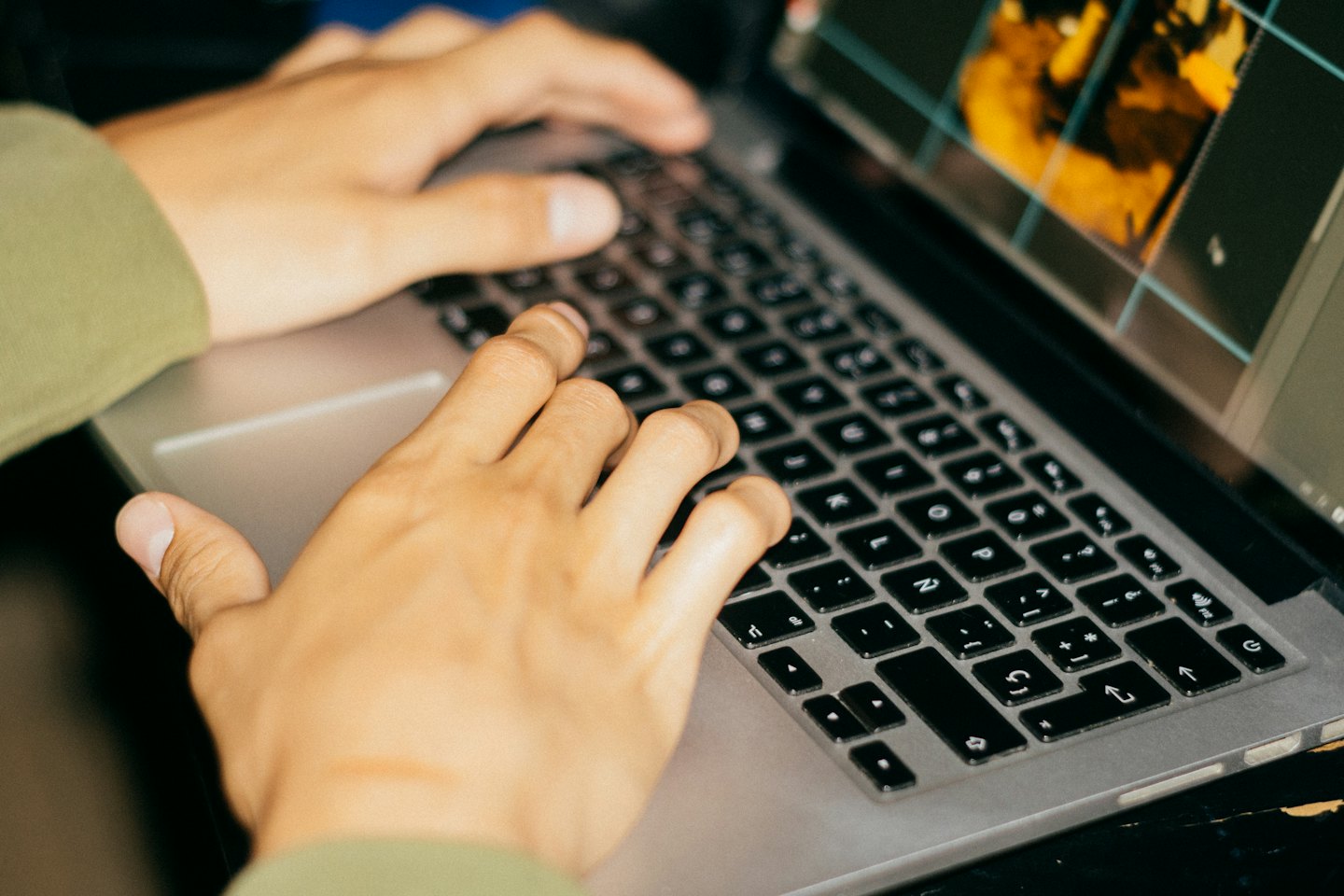 Mani che digitano su una tastiera di laptop con un'interfaccia di editing di immagini.