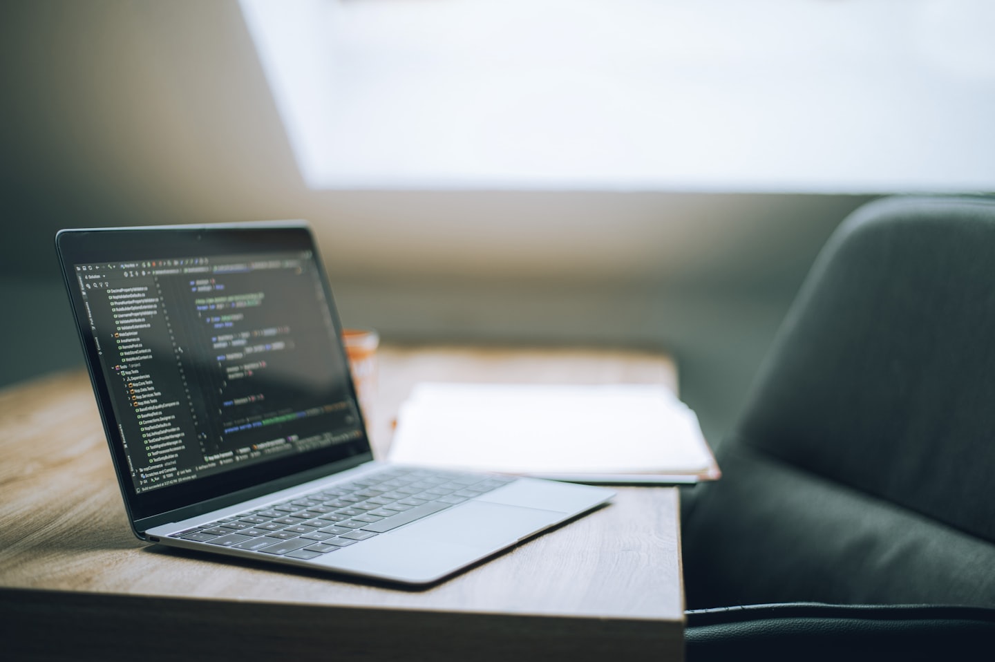 Un laptop con codice di programmazione su una scrivania di legno.