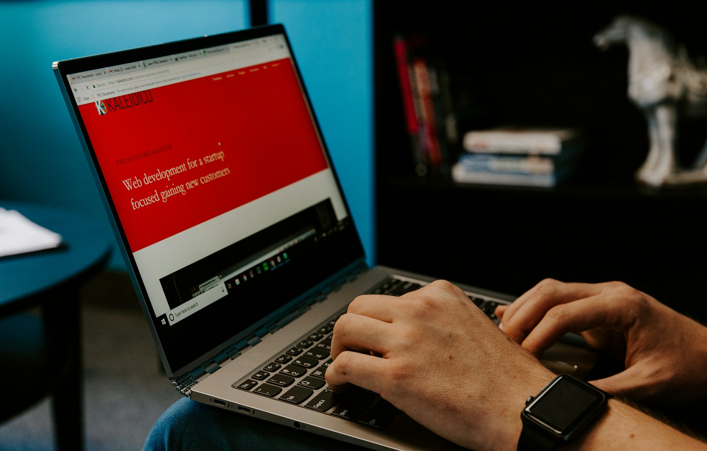 Mani che digitano su un laptop argentato che mostra un sito web.